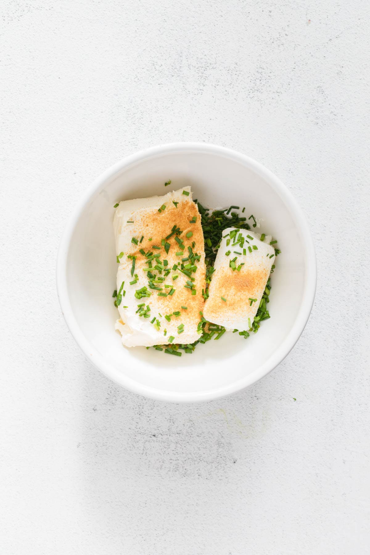 Cream cheese, goat cheese, and garlic powder in a bowl.