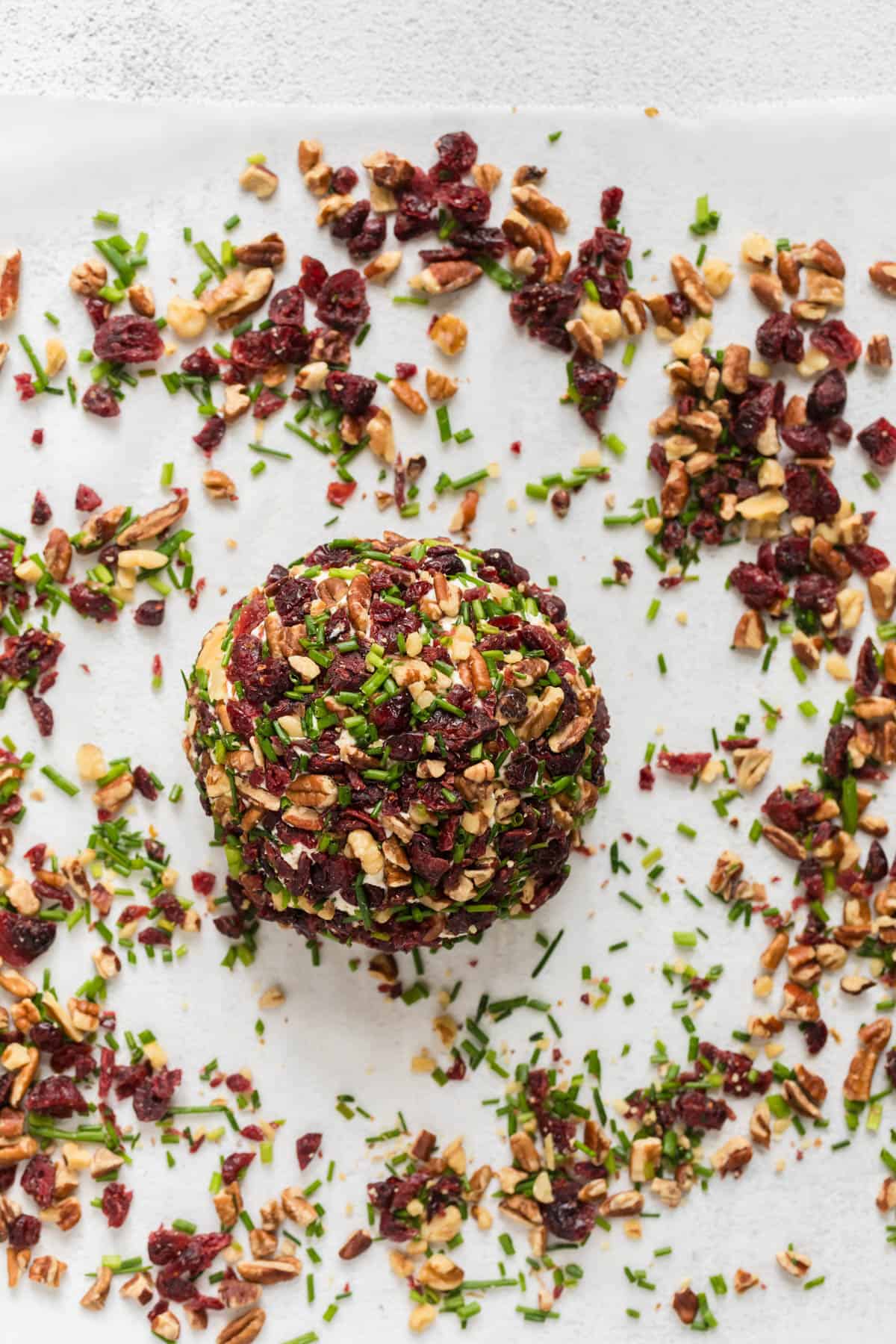 A cheeseball rolled in chopped cranberries, pecans, and chives.