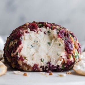 An image of a cranberry pecan cheeseball with part of it scooped out.