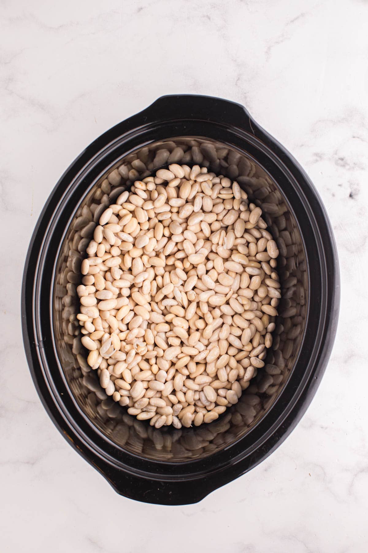 Adding dried beans to a crock pot.