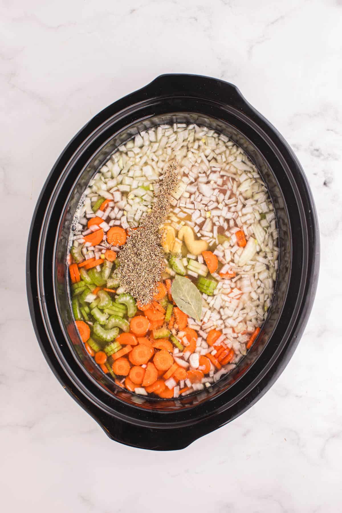 Adding seasonings to a crock pot filled with ham and bean soup.