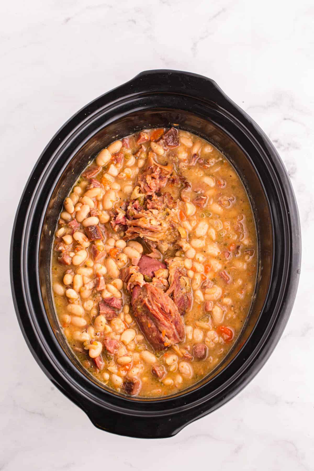 An overhead image of a finished pot of crock pot ham and bean soup.