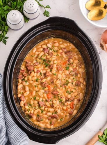 An overhead image of a crock pot full of ham and bean soup.