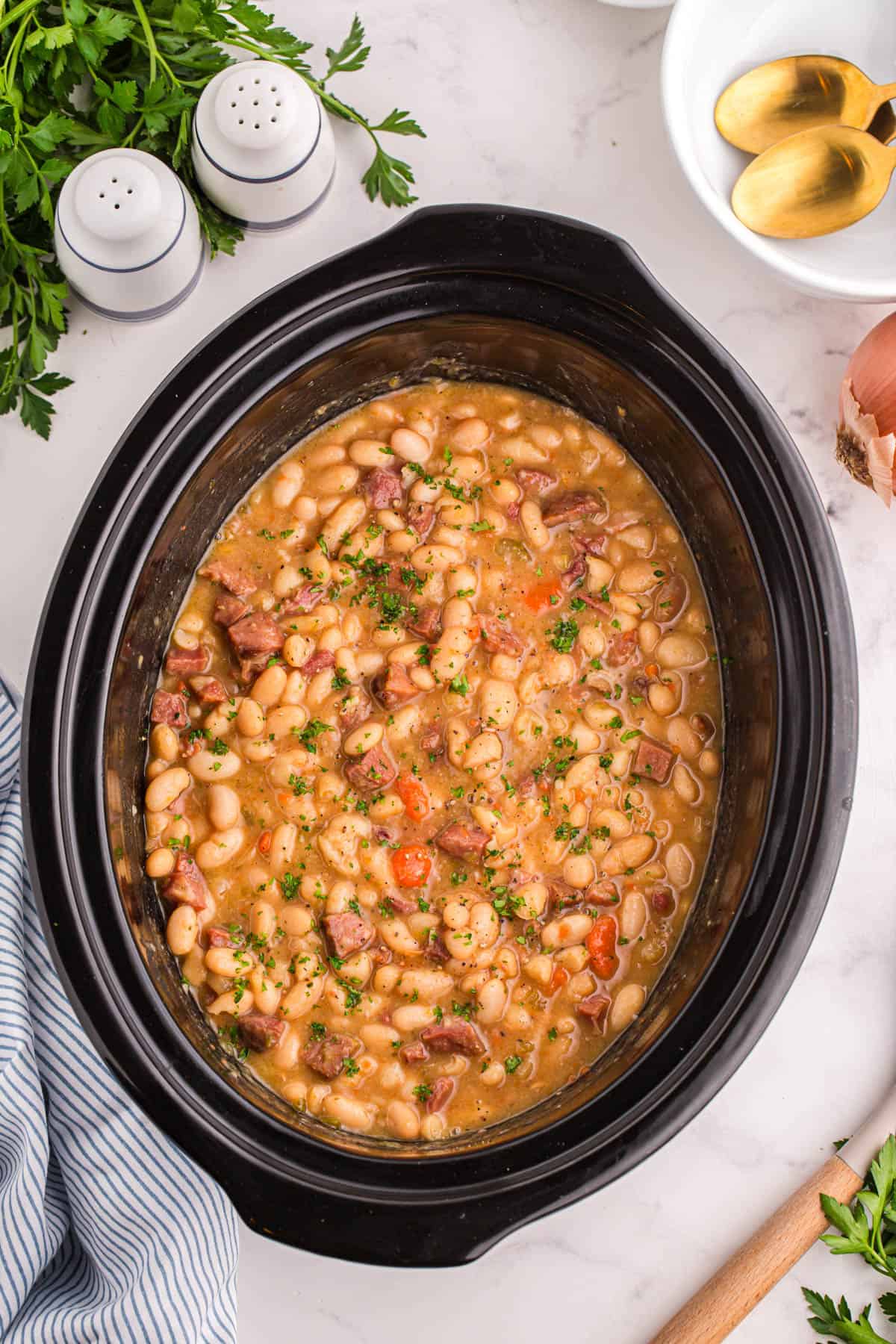 An overhead image of a crock pot full of ham and bean soup.