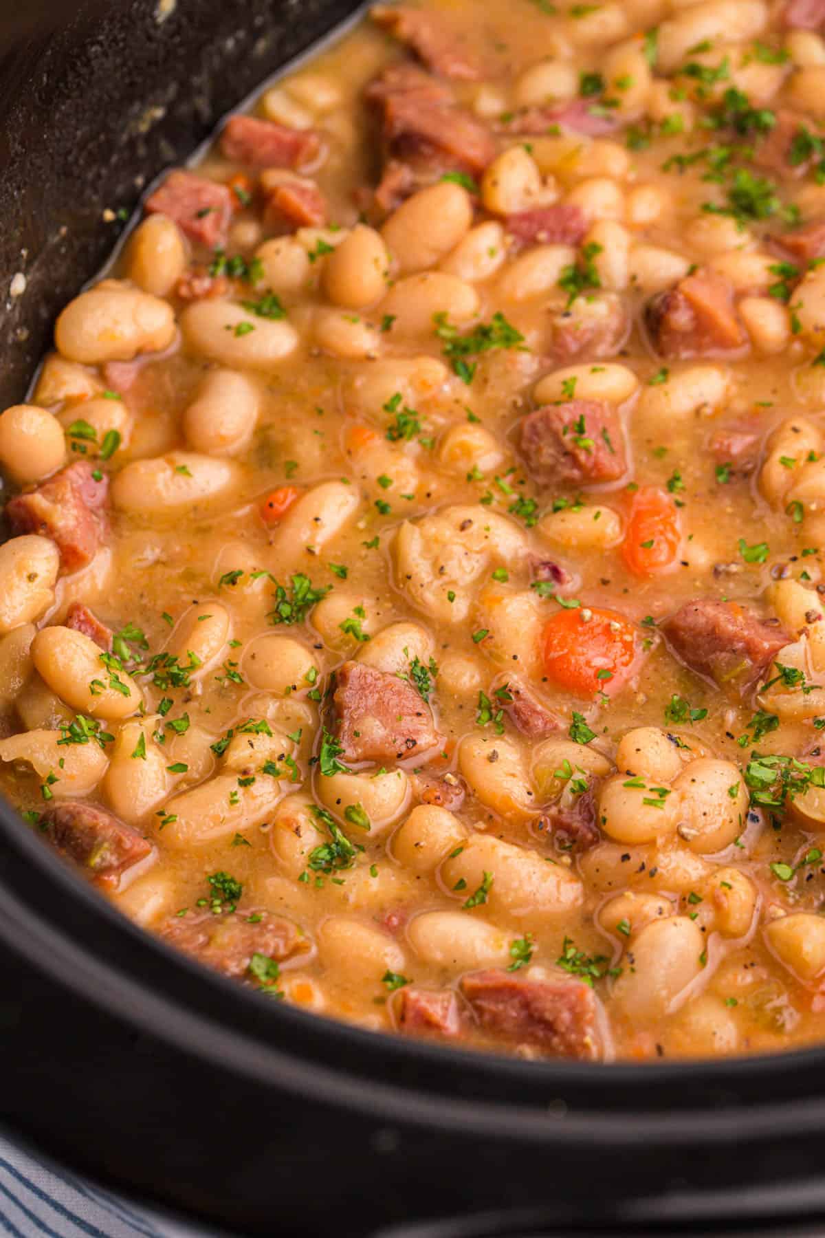 A close up image of ham and bean soup in a crock pot.