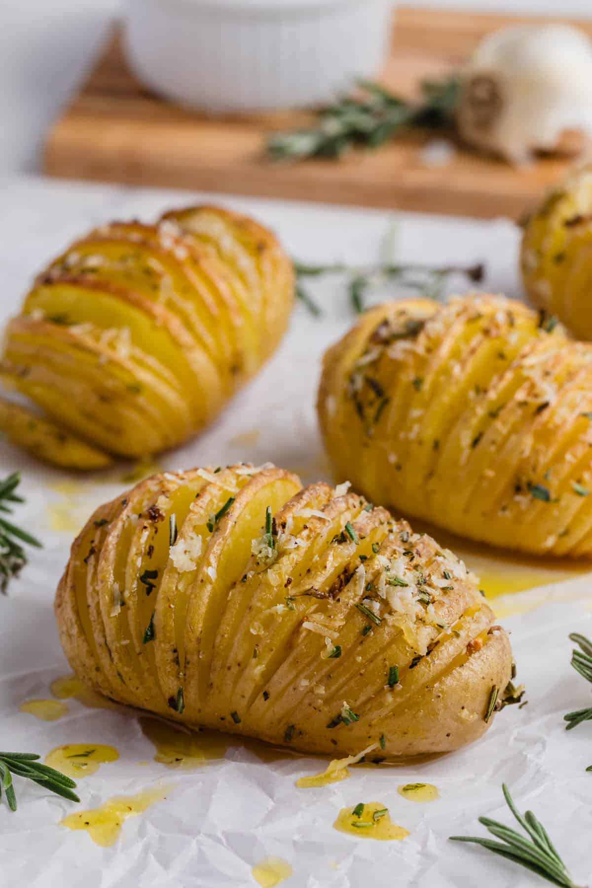 Three hasselback potatoes on parchment paper.