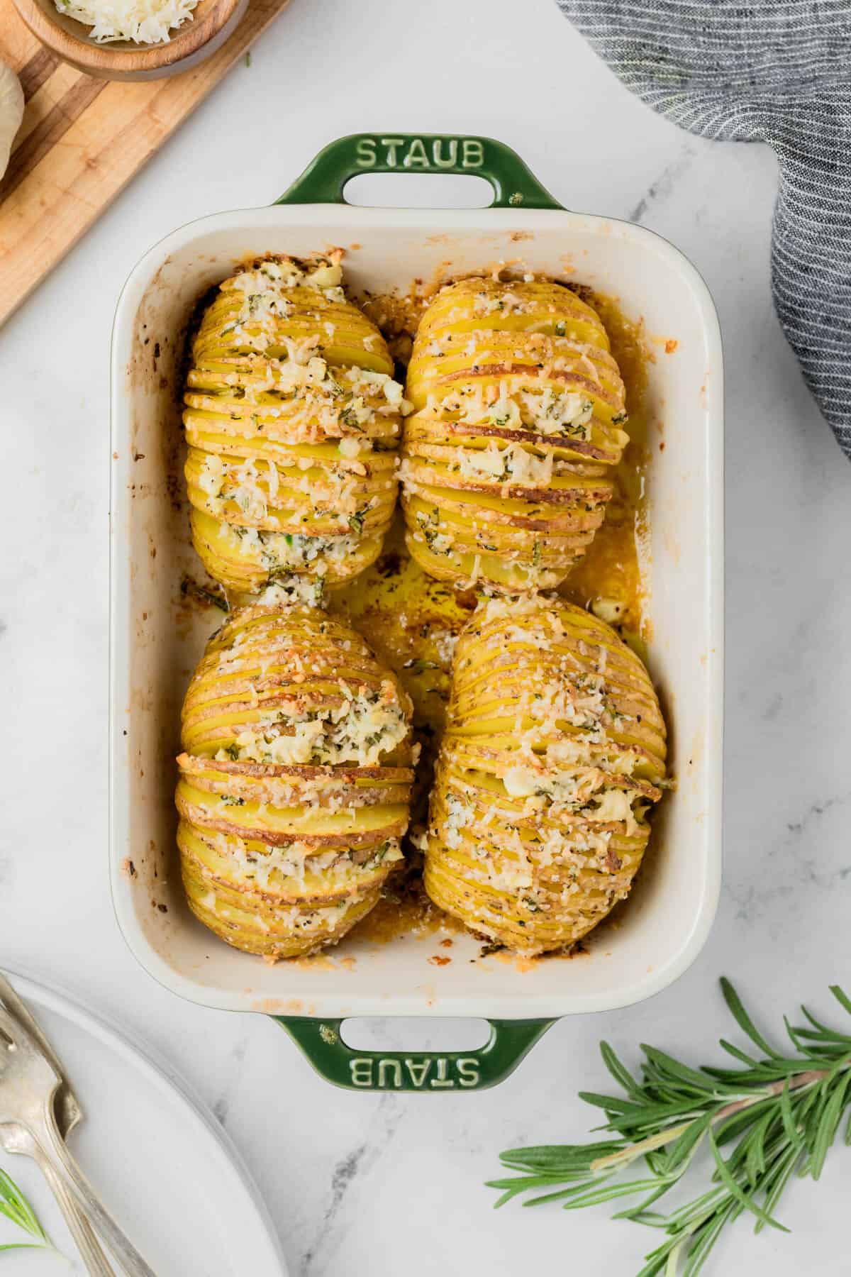 A baking dish with four hasselback potatoes.