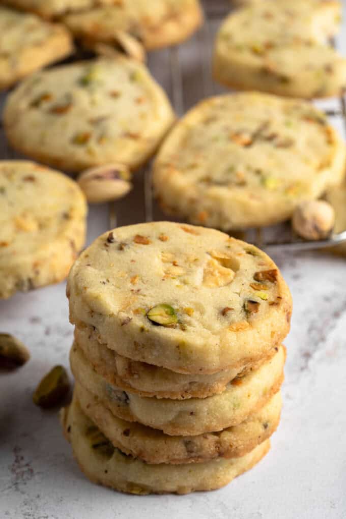 Angled view of a stack of Pistachio Shortbread cookies next to other cookies.