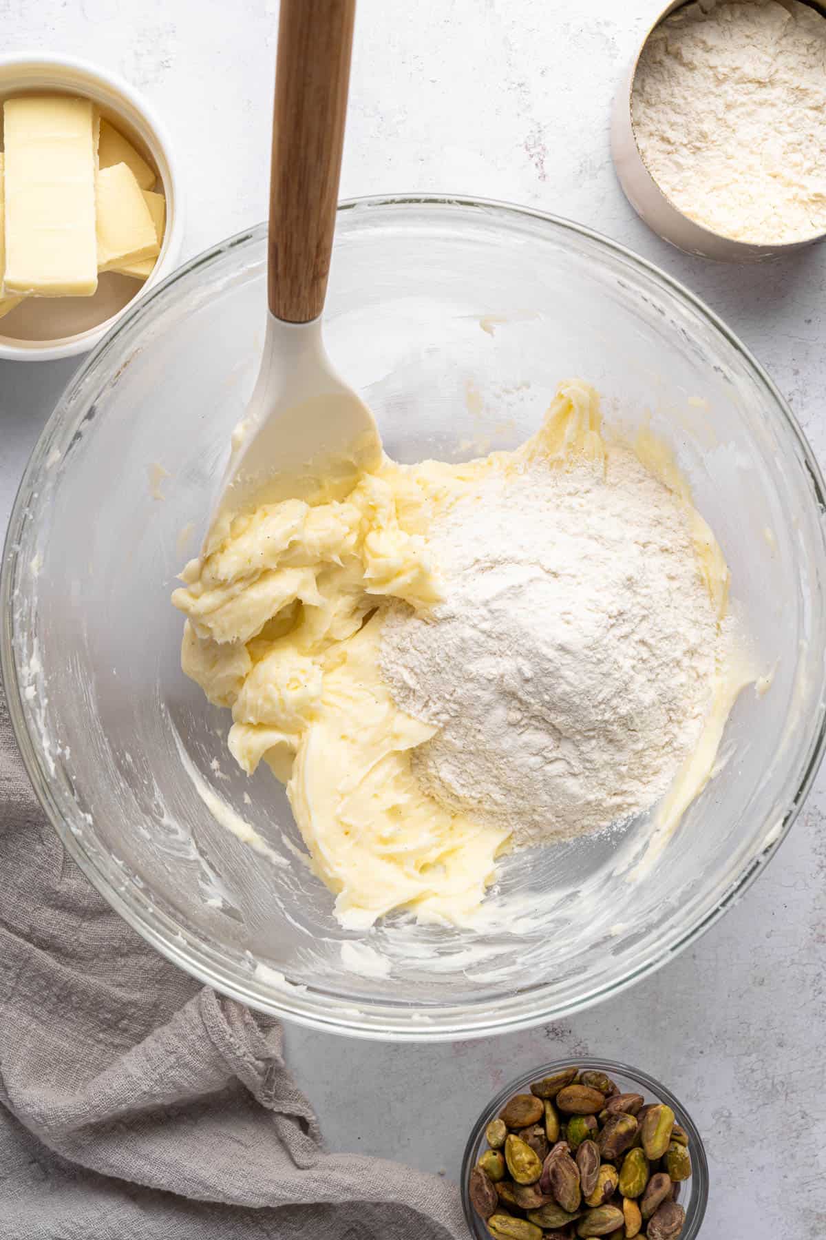 Overhead view of butter sugar mixture with flour added to it in a large bowl.