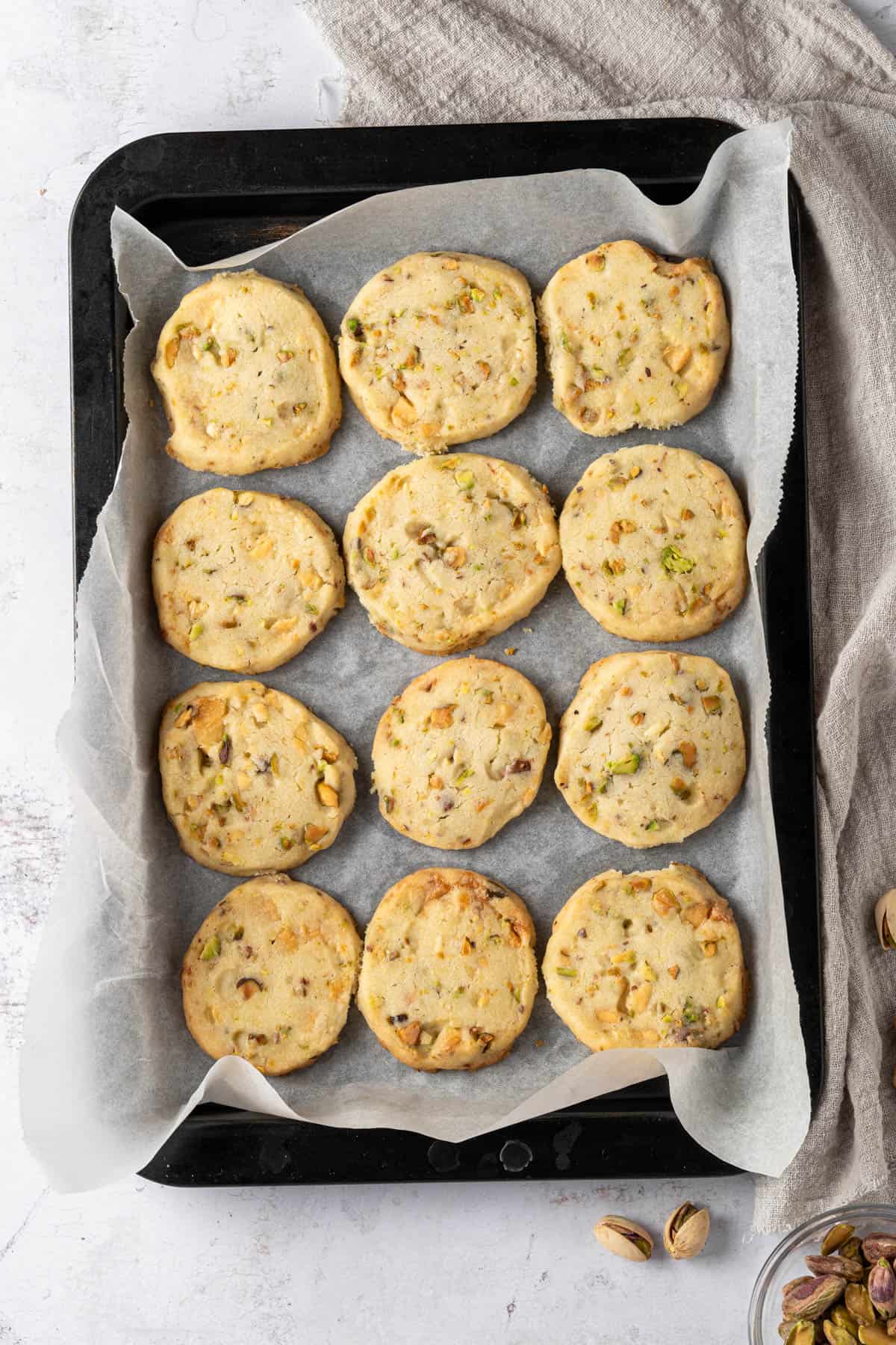 Overhead view of Pistachio Shortbread cookies on a parchment-lined baking tray.