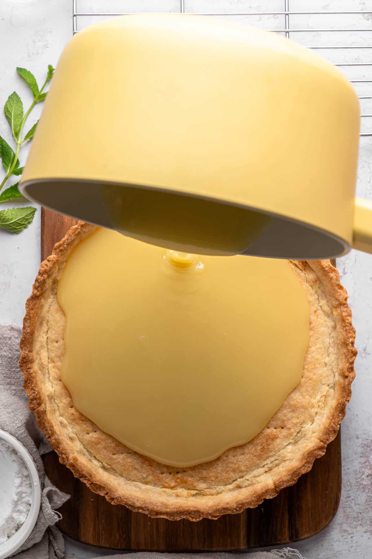 Pouring white chocolate ganache into a tart shell.