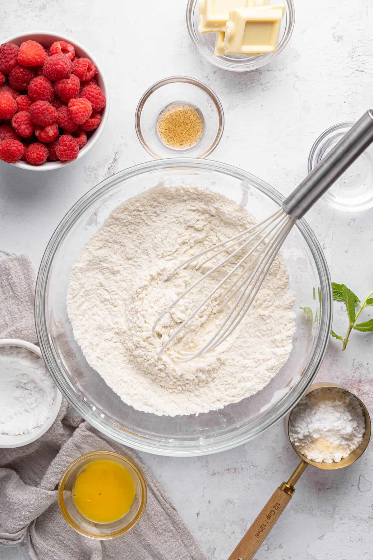 A whisk in a mixing bowl full of flour.