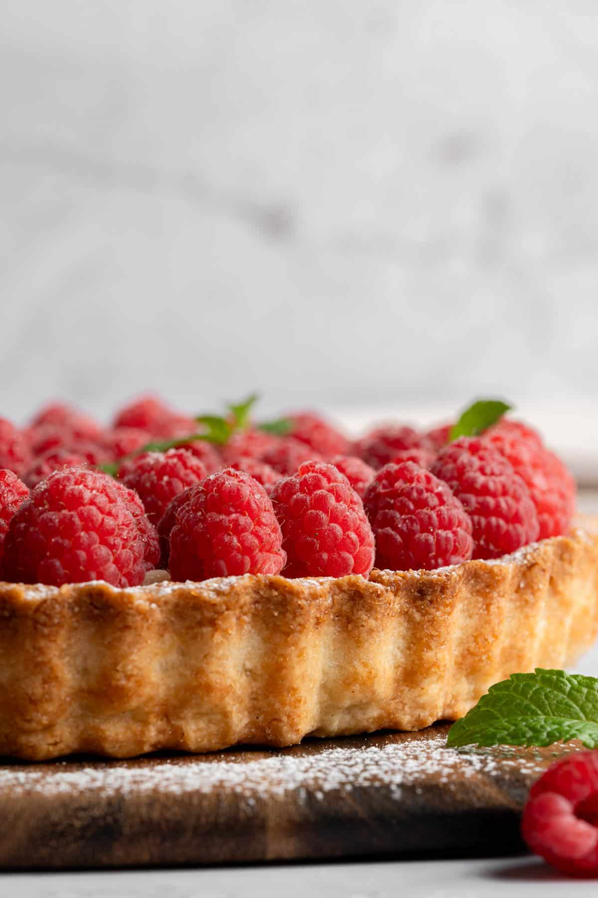 A close up image of a raspberry tart dusted with powdered sugar.