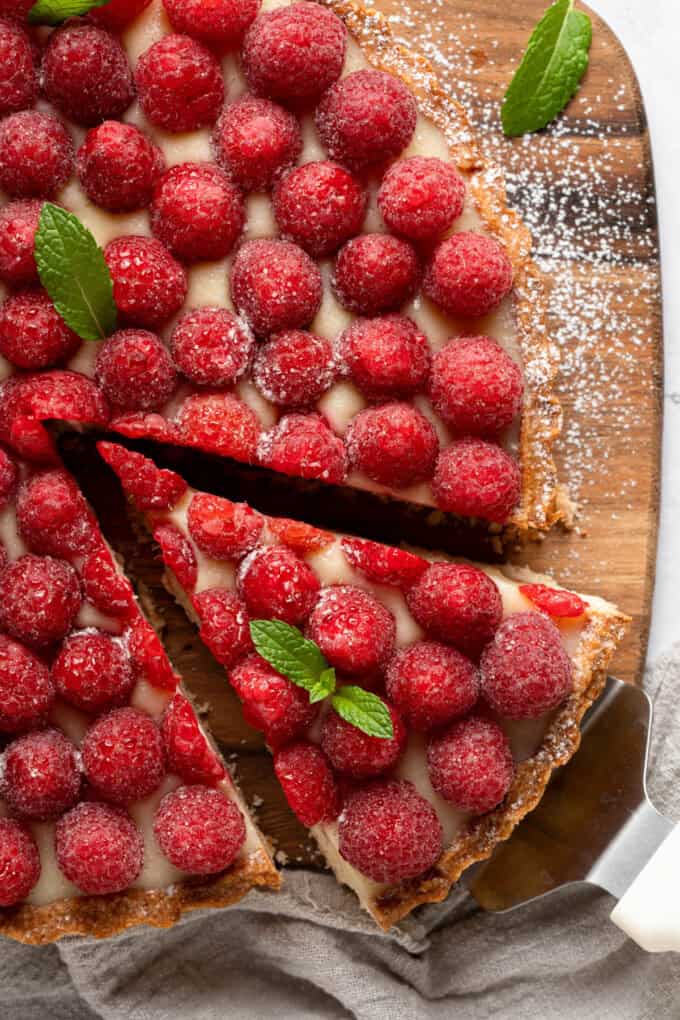 A close image of a slice of raspberry tart being pulled away from the rest of the tart.