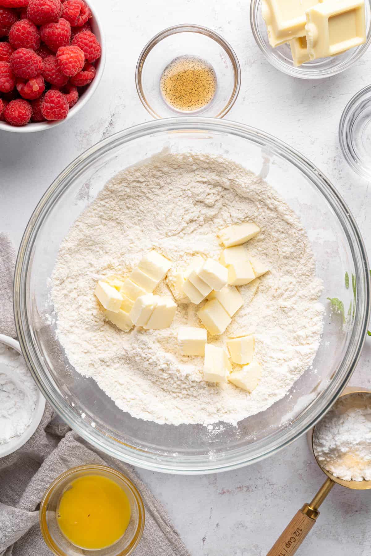 Adding cubed cold butter to flour in a mixing bowl.