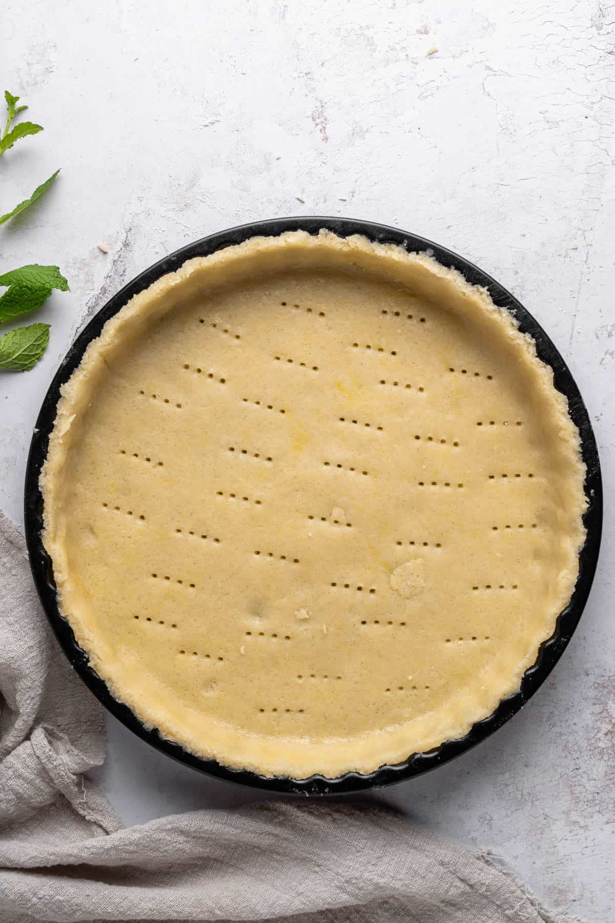 A pastry crust pricked with a fork in a tart pan.