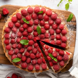 An overhead image of a raspberry chocolate tart with a slice being removed.