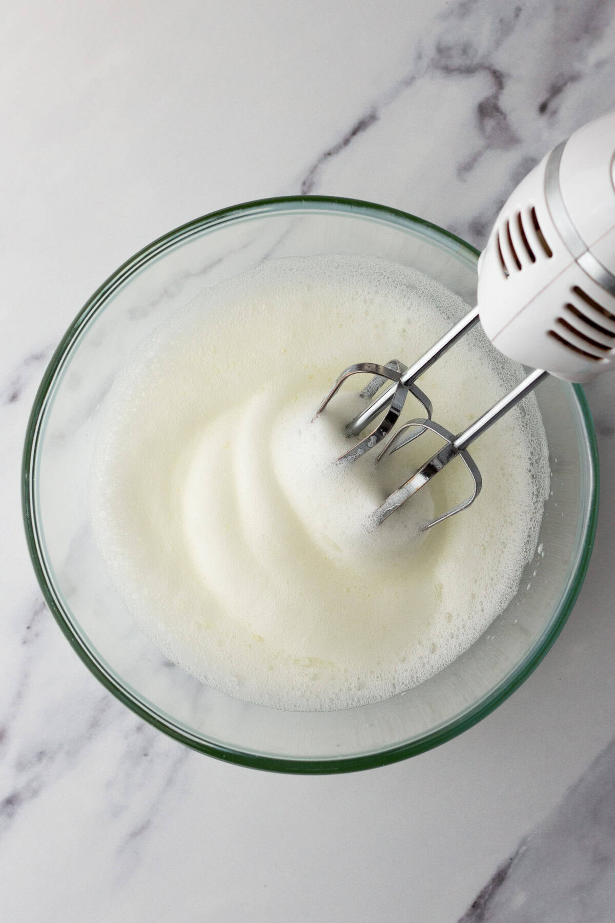 Mixing egg whites and sugar in a mixing bowl.