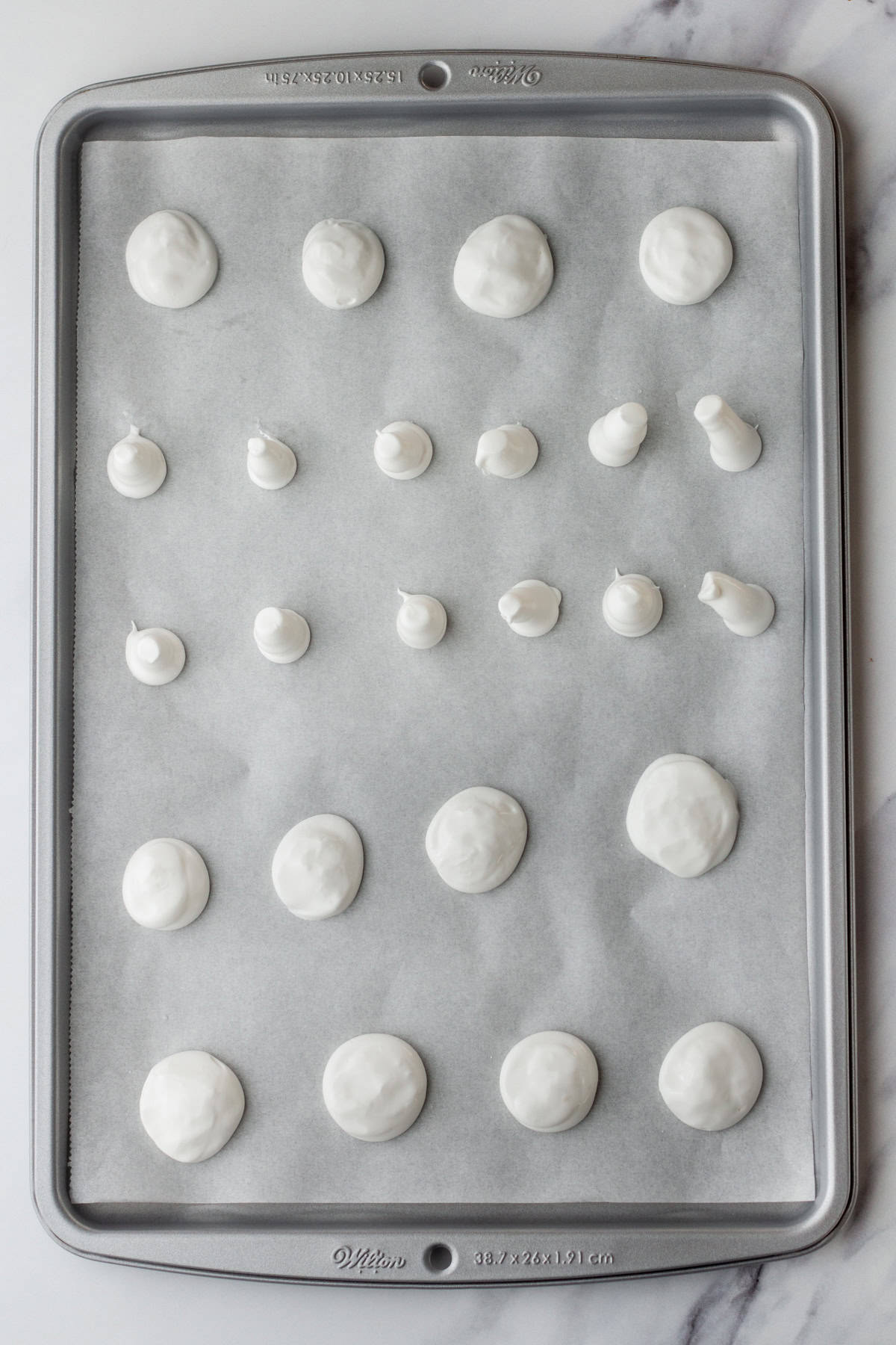 Piping circles and stems to make meringue mushrooms.