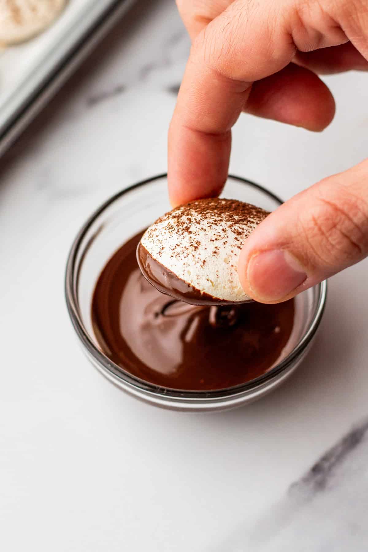 Dipping meringue mushroom tops in melted chocolate.