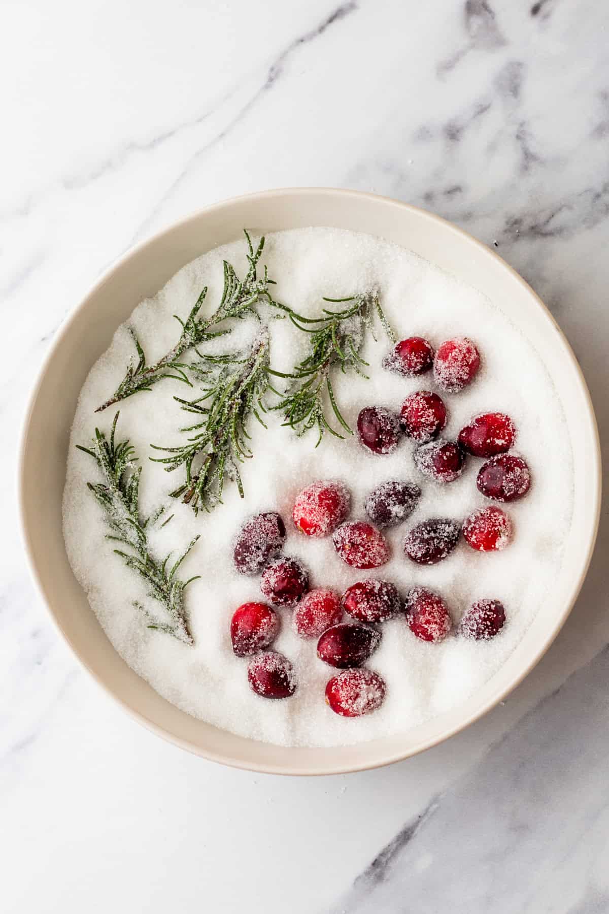 Coating rosemary and cranberries in sugar.