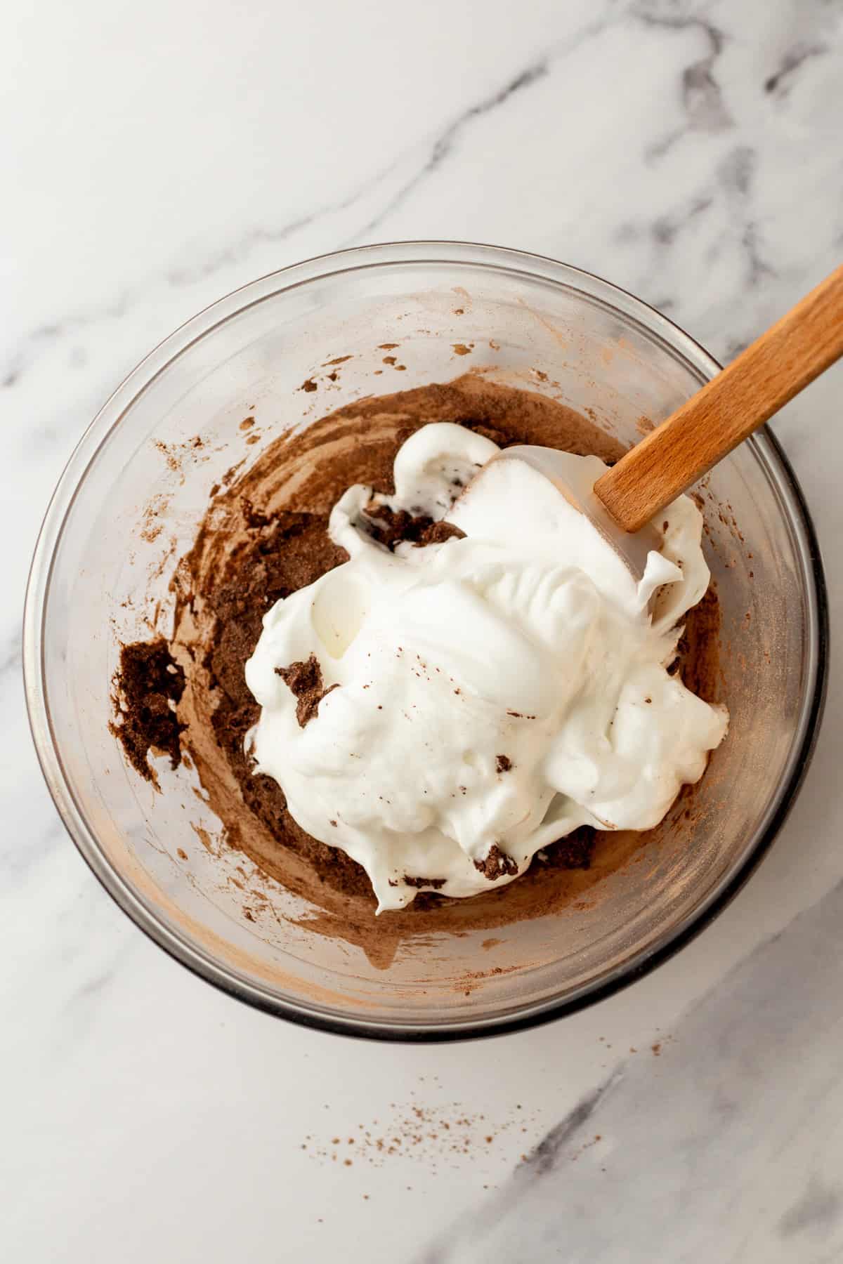 Folding whipped egg whites into cake batter.