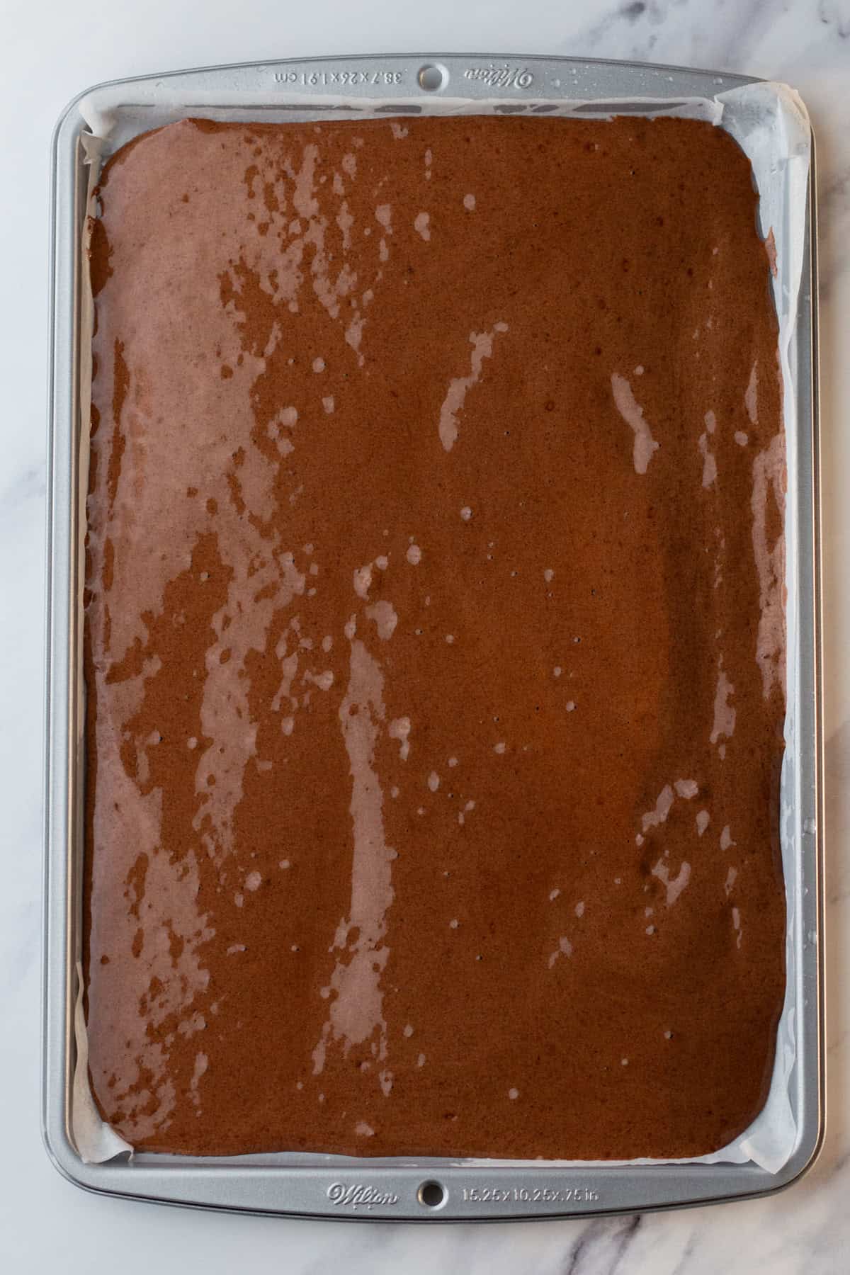 Chocolate cake batter in a jelly roll pan.