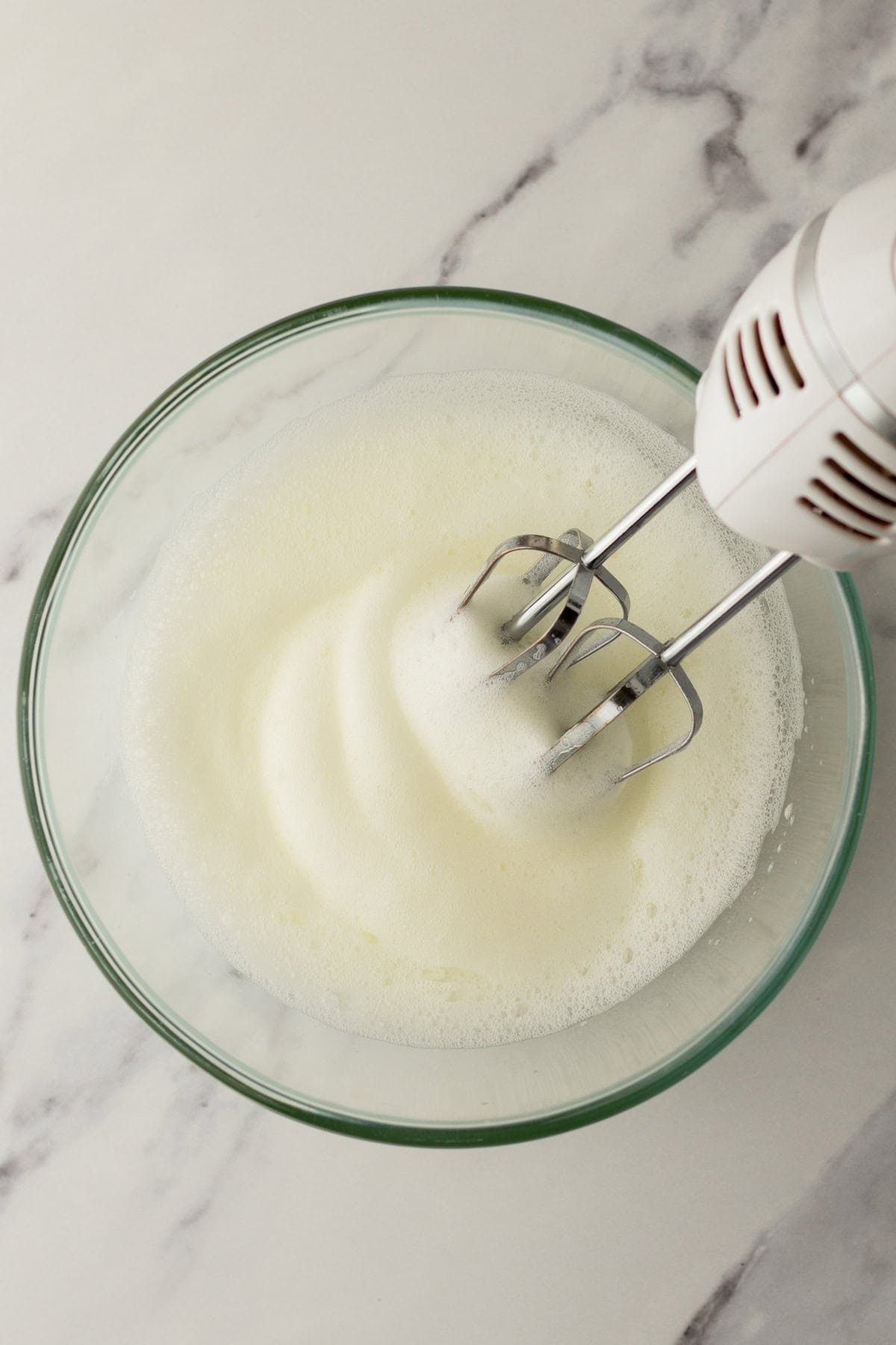 Foamy egg whites in a mixing bowl.