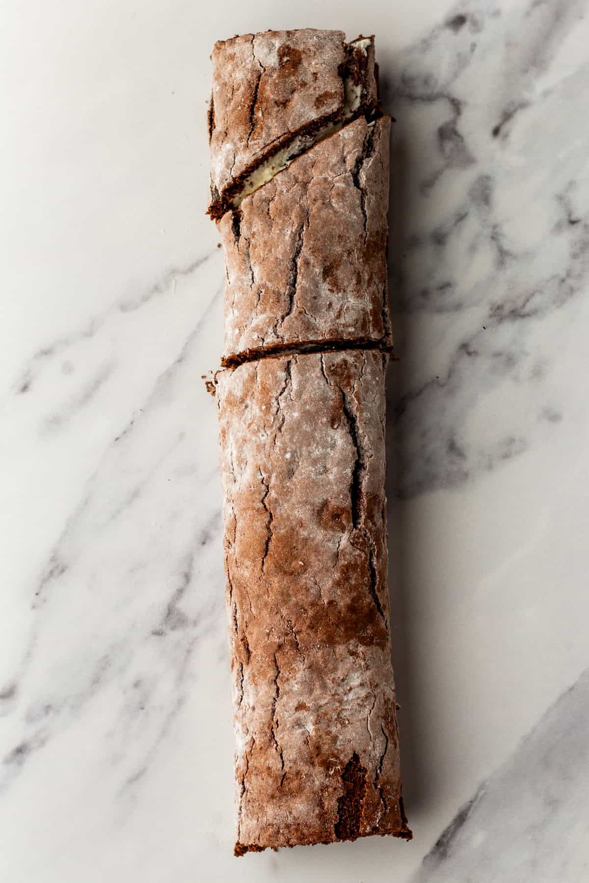 Cutting a swiss cake roll into sections for making a yule log.