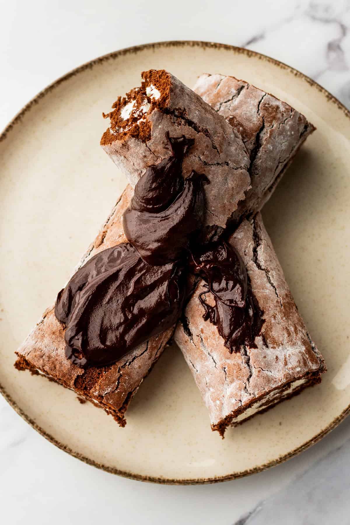 Frosting a yule log cake with chocolate ganache.