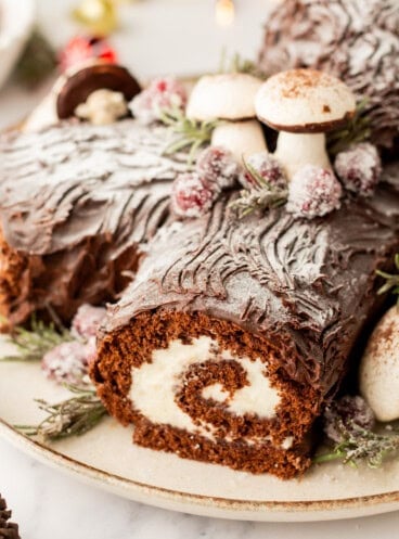 A close image of a festive yule love buche de noel cake with meringue mushrooms.