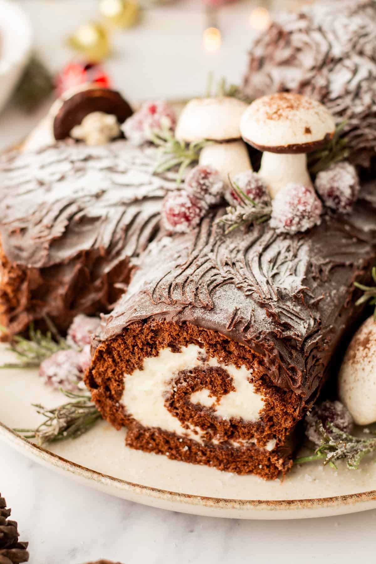 A close image of a festive yule love buche de noel cake with meringue mushrooms.