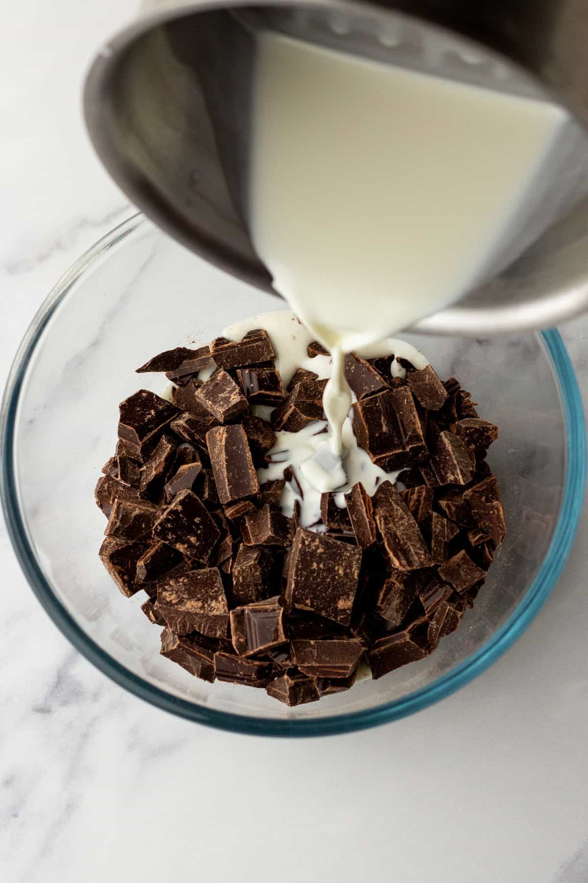 Pouring hot cream over chopped chocolate in a bowl