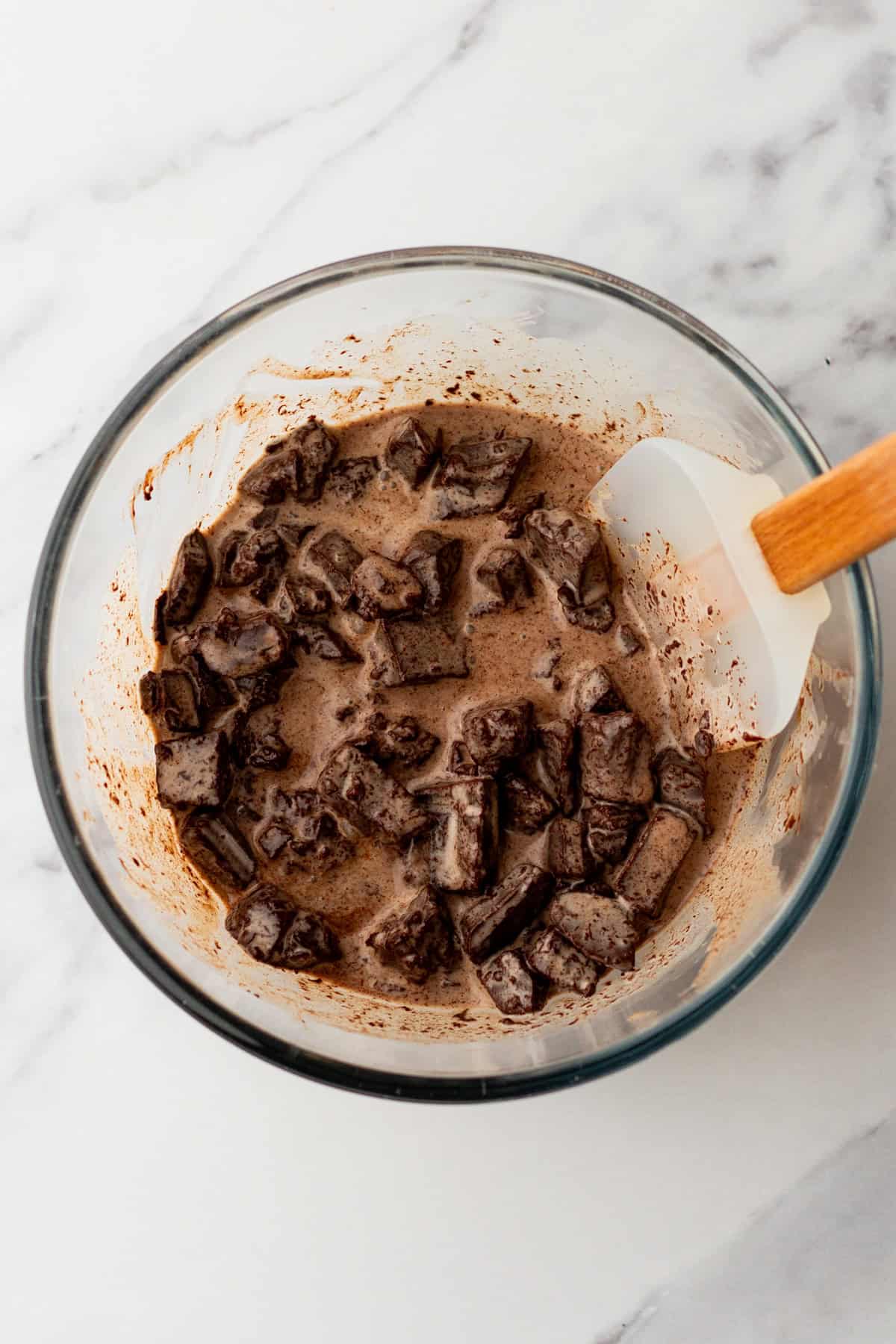 Stirring chopped chocolate and hot cream to make ganache.