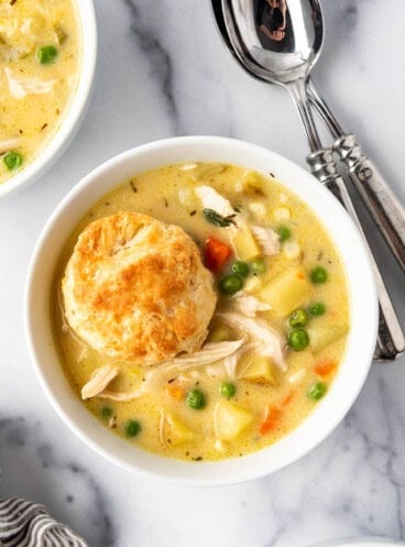 A close image of a bowl of chicken pot pie soup with a biscuit in it.