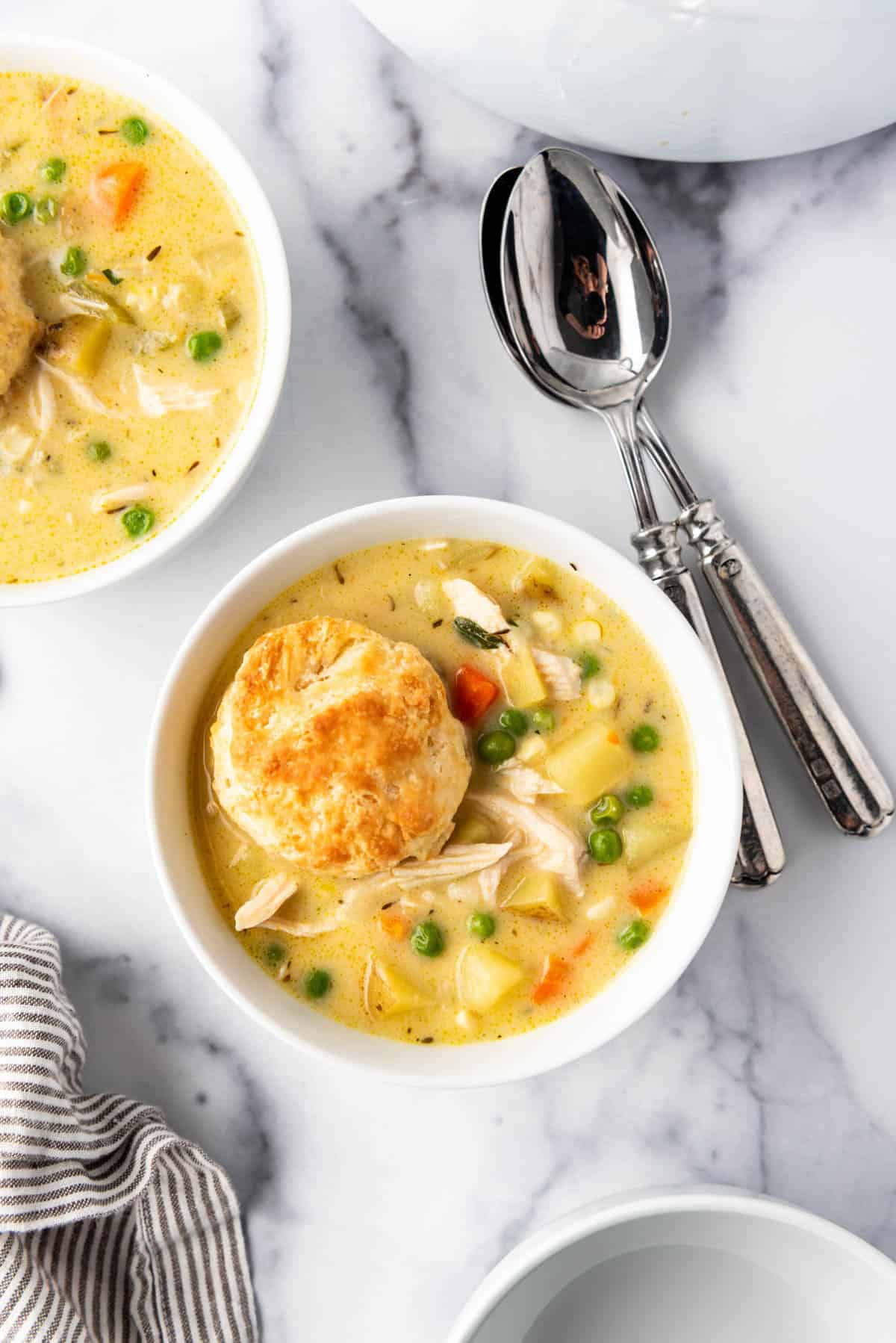 A golden brown biscuit in a bowl of chicken pot pie soup.