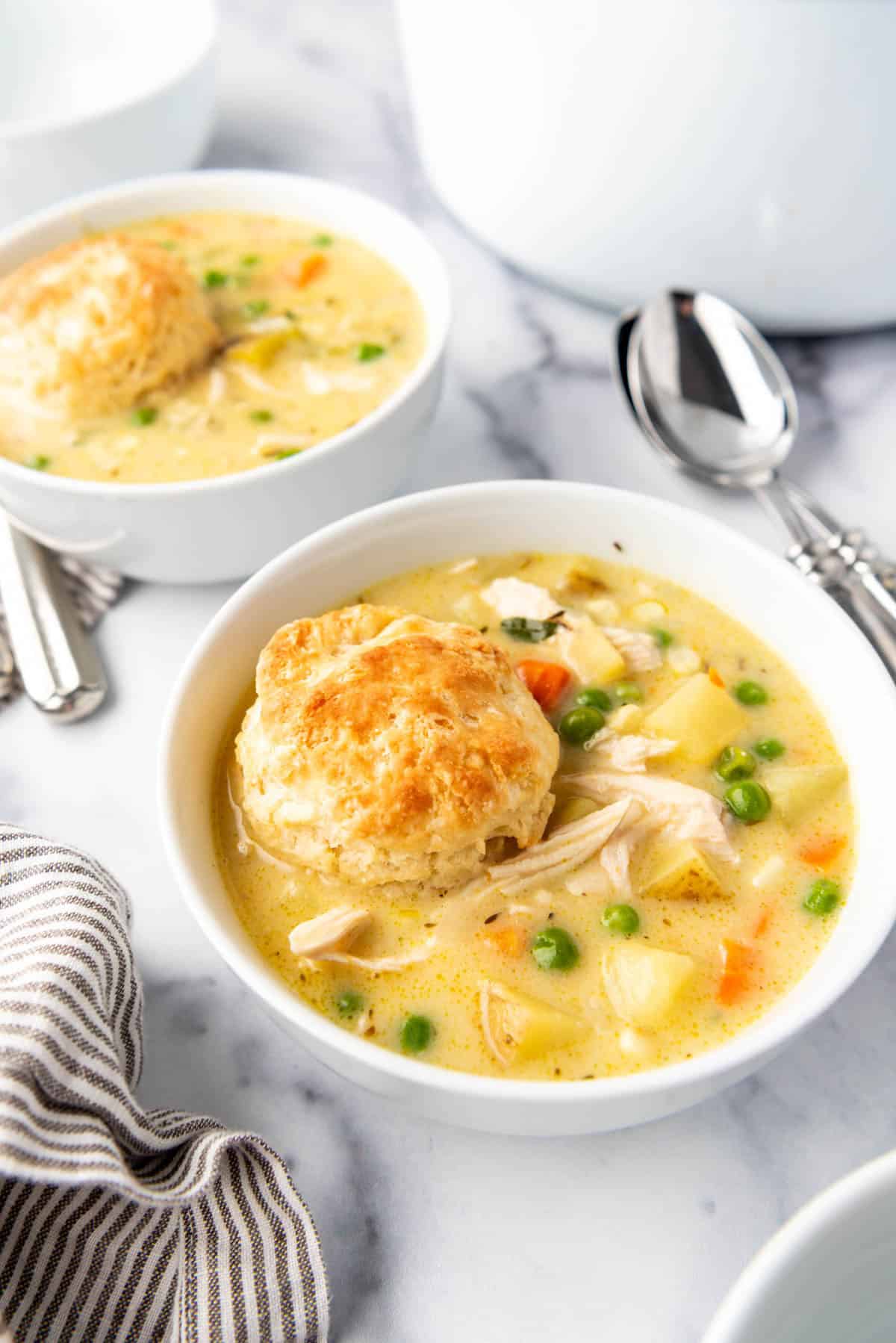 A side image of bowls of chicken pot pie soup in white bowls.