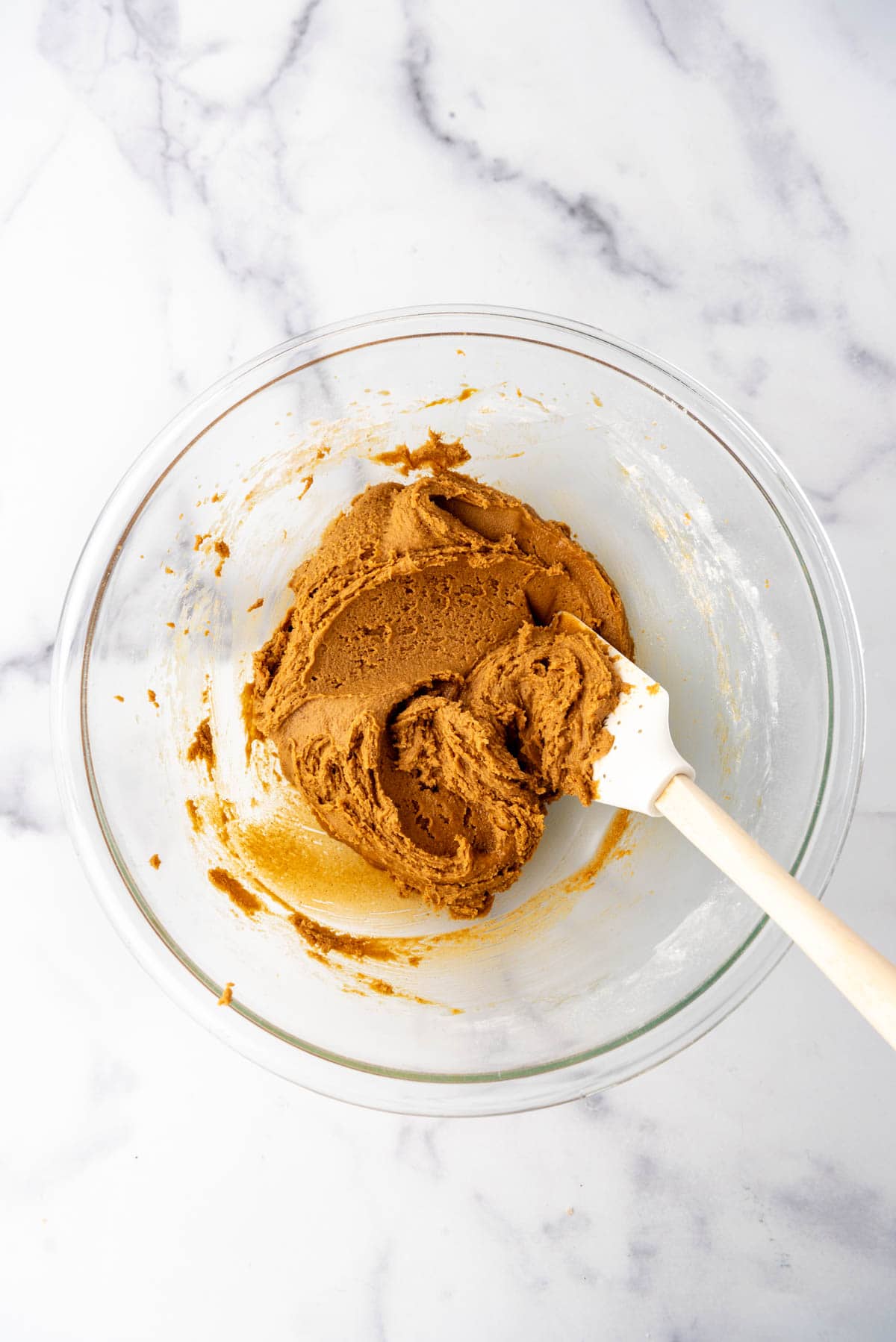 Soft gingerbread cookie dough in a bowl with a spatula.