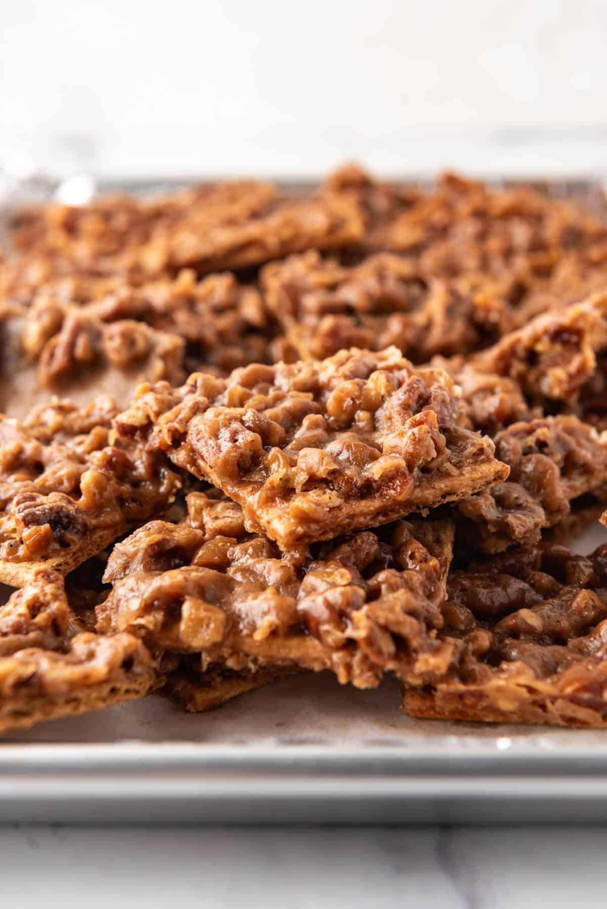 An image of pecan pie bark piled on a baking sheet lined with aluminum foil.