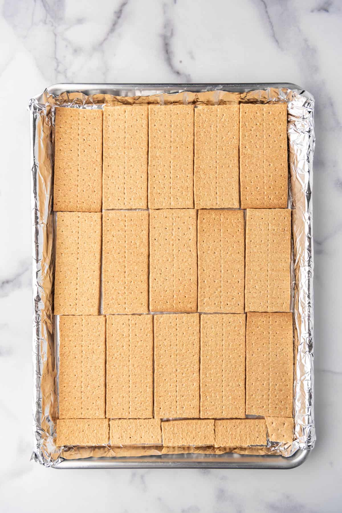 Graham cracker sheets placed in a single layer on a baking sheet lined with foil.