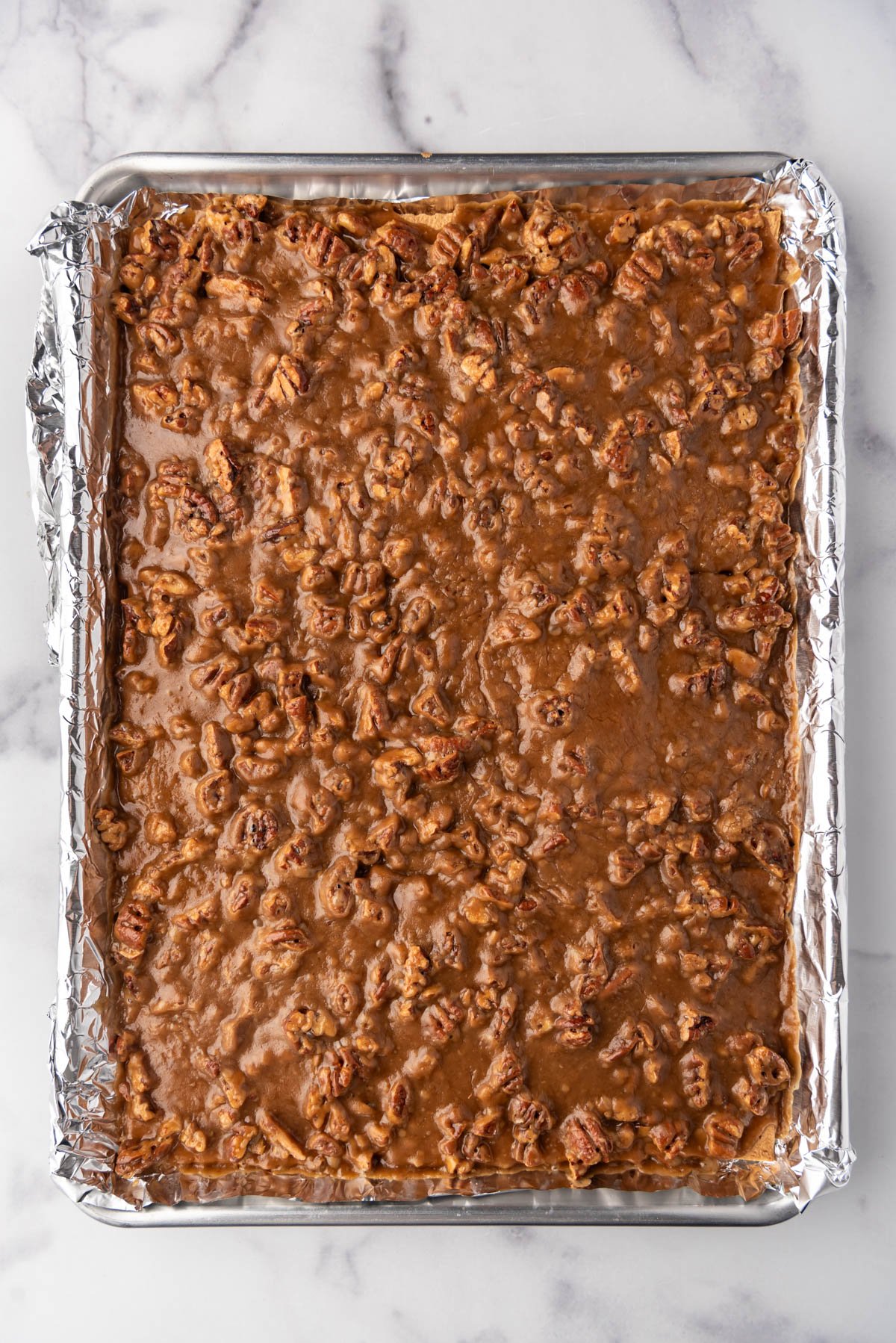 An overhead image of a sheet of baked pecan pie bark.