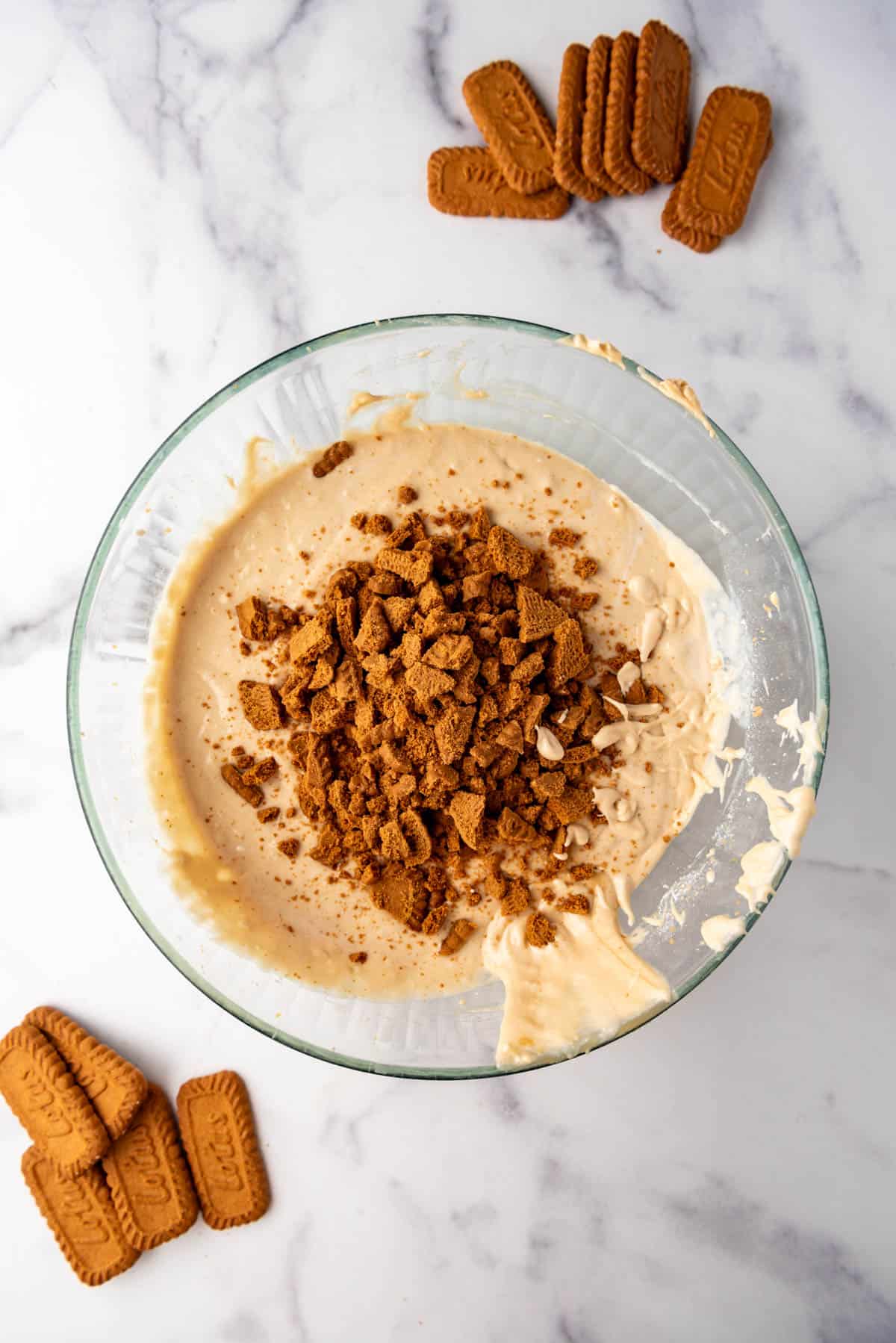 Adding roughly crushed Biscoff cookies to cake batter.