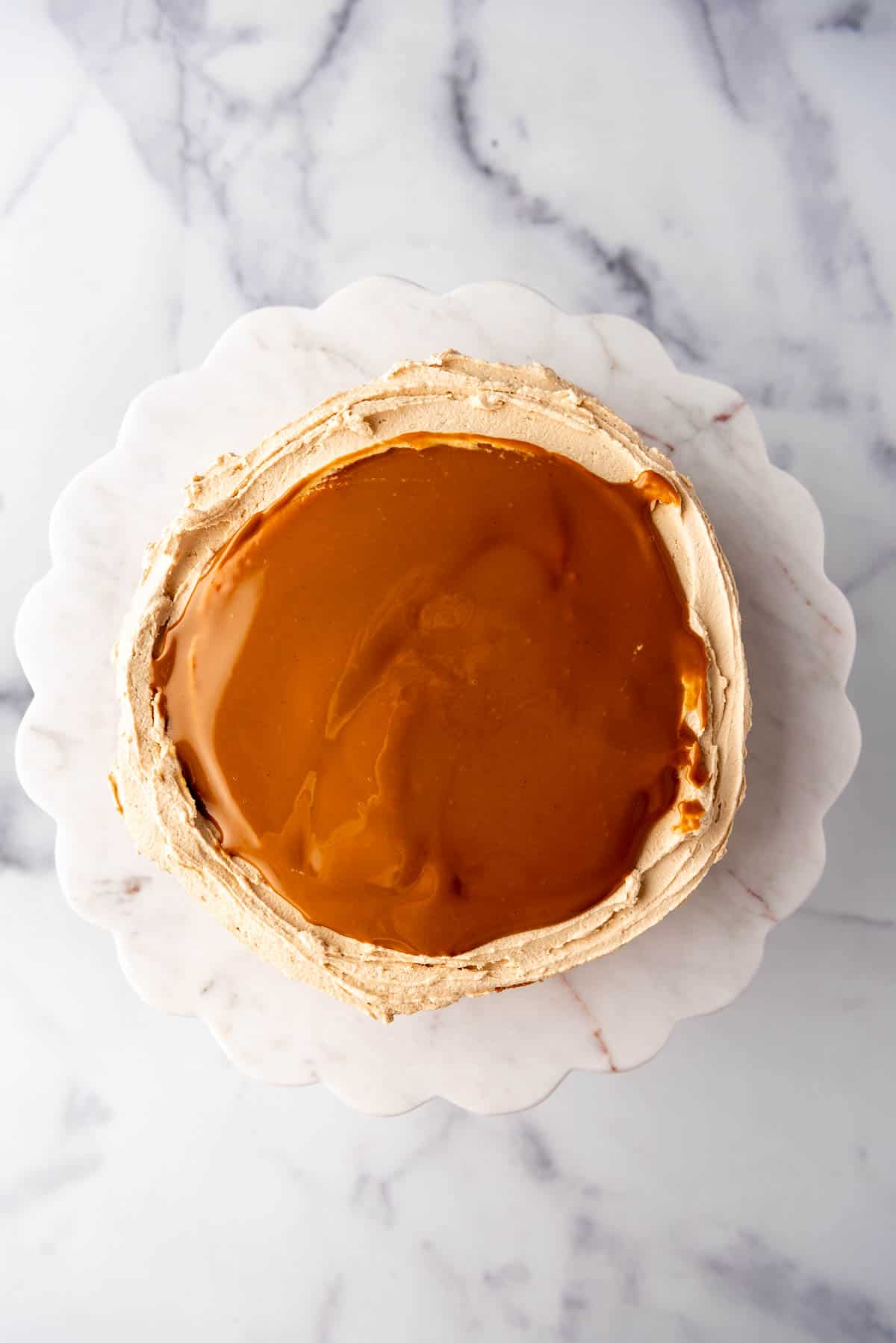 Adding a layer of melted cookie butter to a cake.