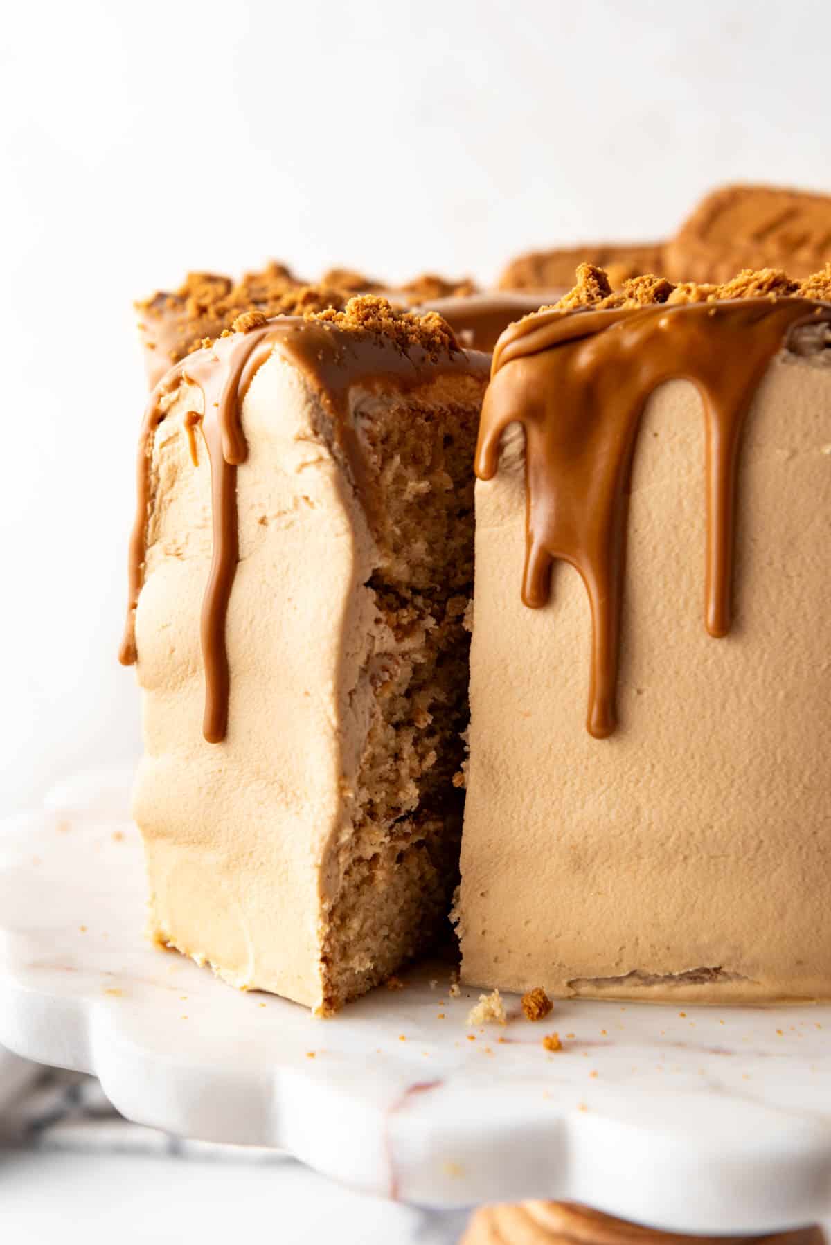 A tall,thick slice of Biscoff cookie butter cake on a cake stand.