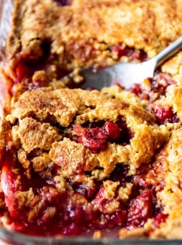 A close up image of a scoop of cherry pineapple dump cake with a serving spoon.