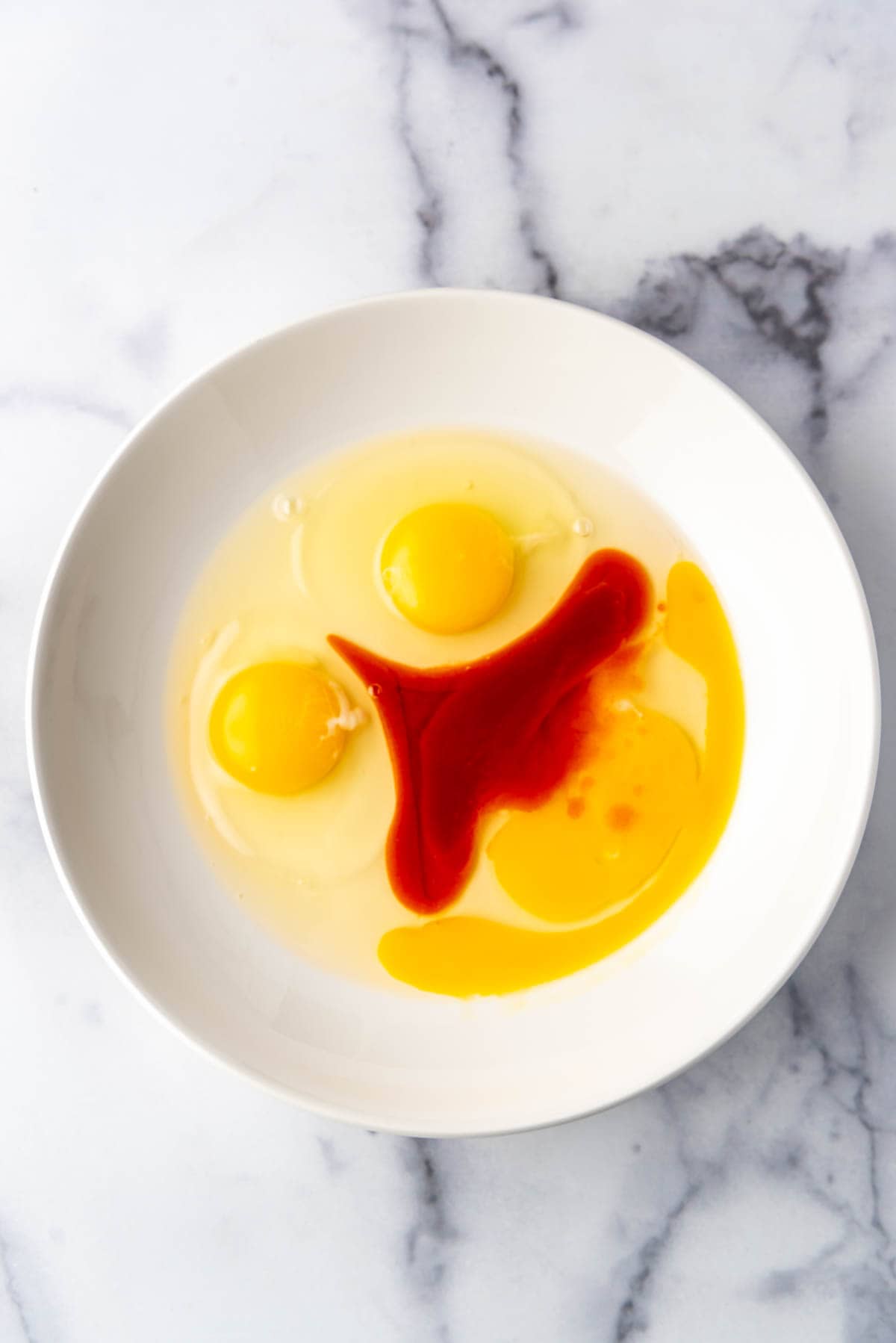 Eggs and hot sauce in a shall bowl.