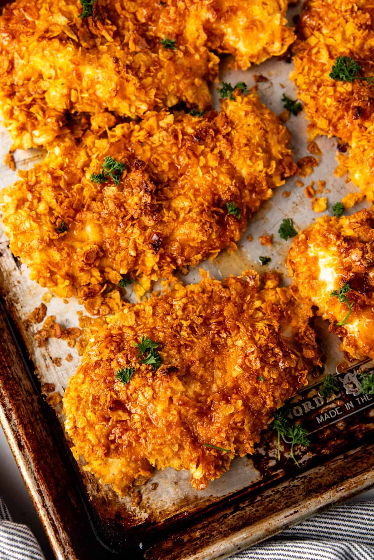 A close overhead image of baked cornflake chicken on a baking sheet.