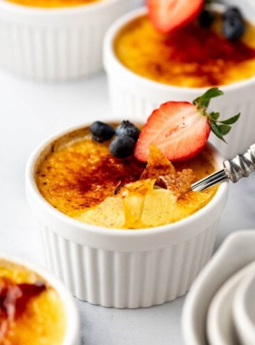 A close side angle view of creme brulee with shards of torched sugar on top.