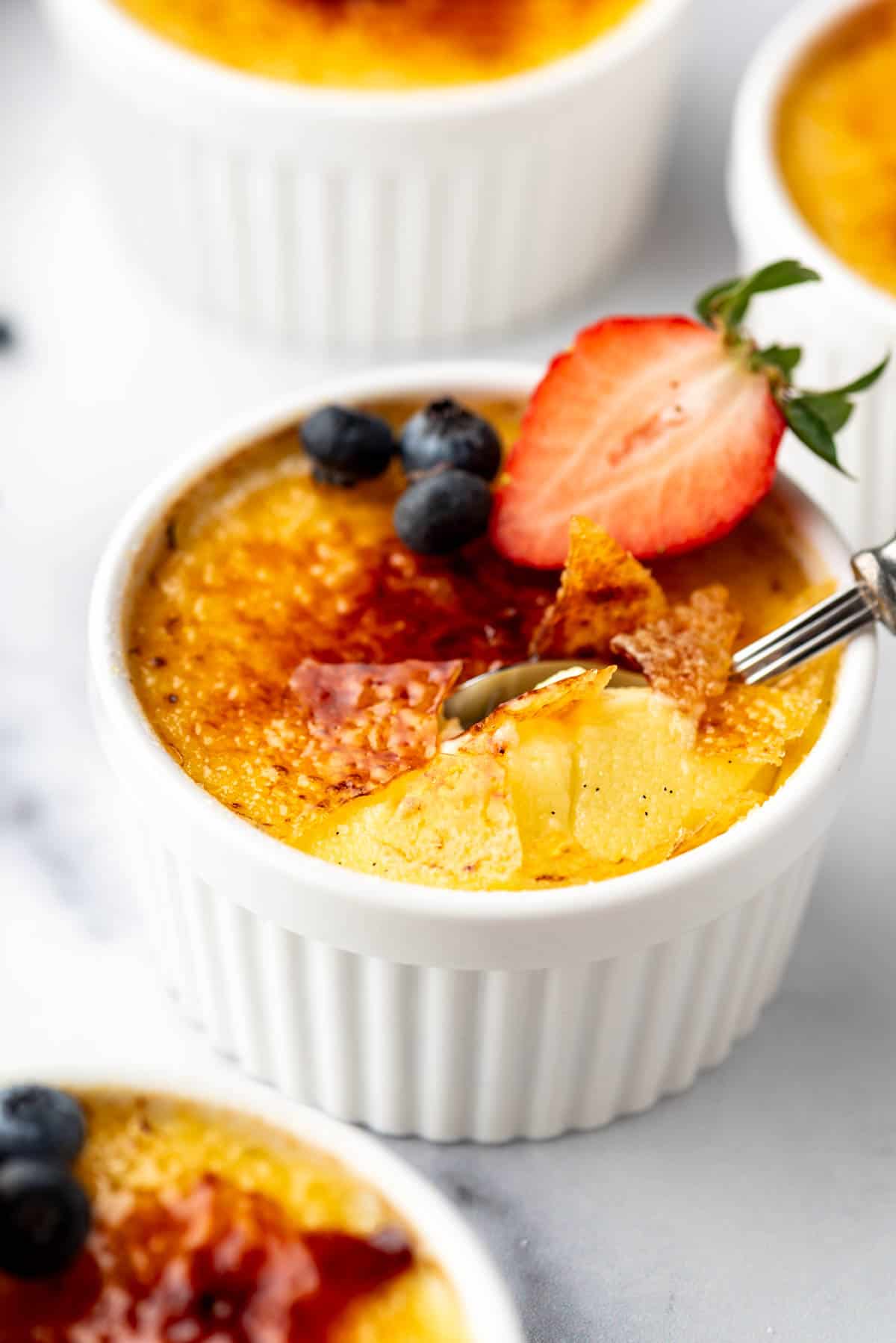 A close side angle view of creme brulee with shards of torched sugar on top.