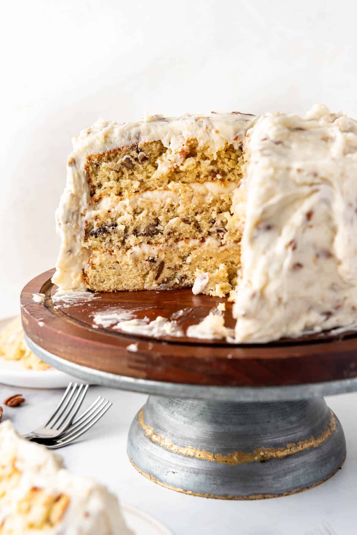 Un gâteau crème italienne partiellement tranché sur un support à gâteau.